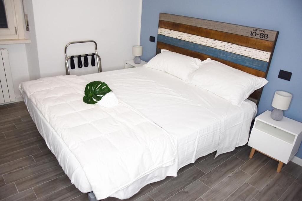 Una cama bien hecha con ropa blanca y una planta verde a la izquierda.