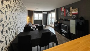 Ein modernes Wohnzimmer mit Essbereich, Küche und einem Balkon mit Blick.