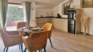 Una cucina moderna con zona pranzo, che include un tavolo rotondo con sedie, un frigorifero e vista su spazi verdi.