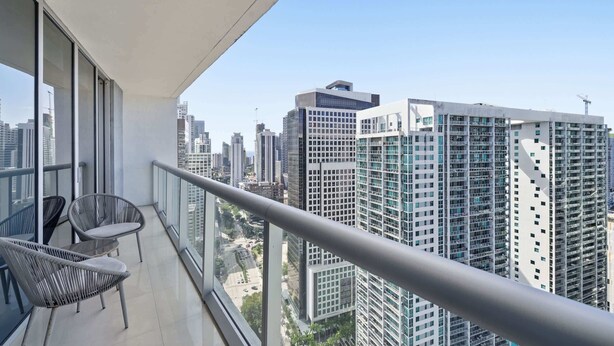 Ein Balkon mit zwei Korbstühlen und Blick auf hohe Gebäude.