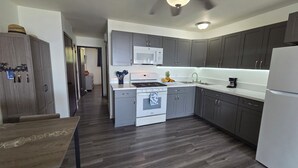 Une cuisine moderne avec des meubles gris, une cuisinière blanche et un four à micro-ondes.