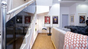 A modern interior with a staircase, a sofa, and artwork on the walls. - Qlets Prive's Shortlets (Abuja)