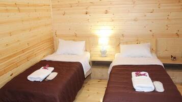 Habitación de cabaña de madera con dos camas, cada una con colcha marrón y almohadas blancas.