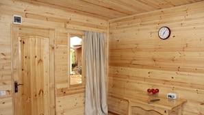 A wooden room with a door, a window with curtains, a table with apples and a radio, and a clock on the wall. - GREEN VILLA TSKALTUBO (Tsqaltubo)