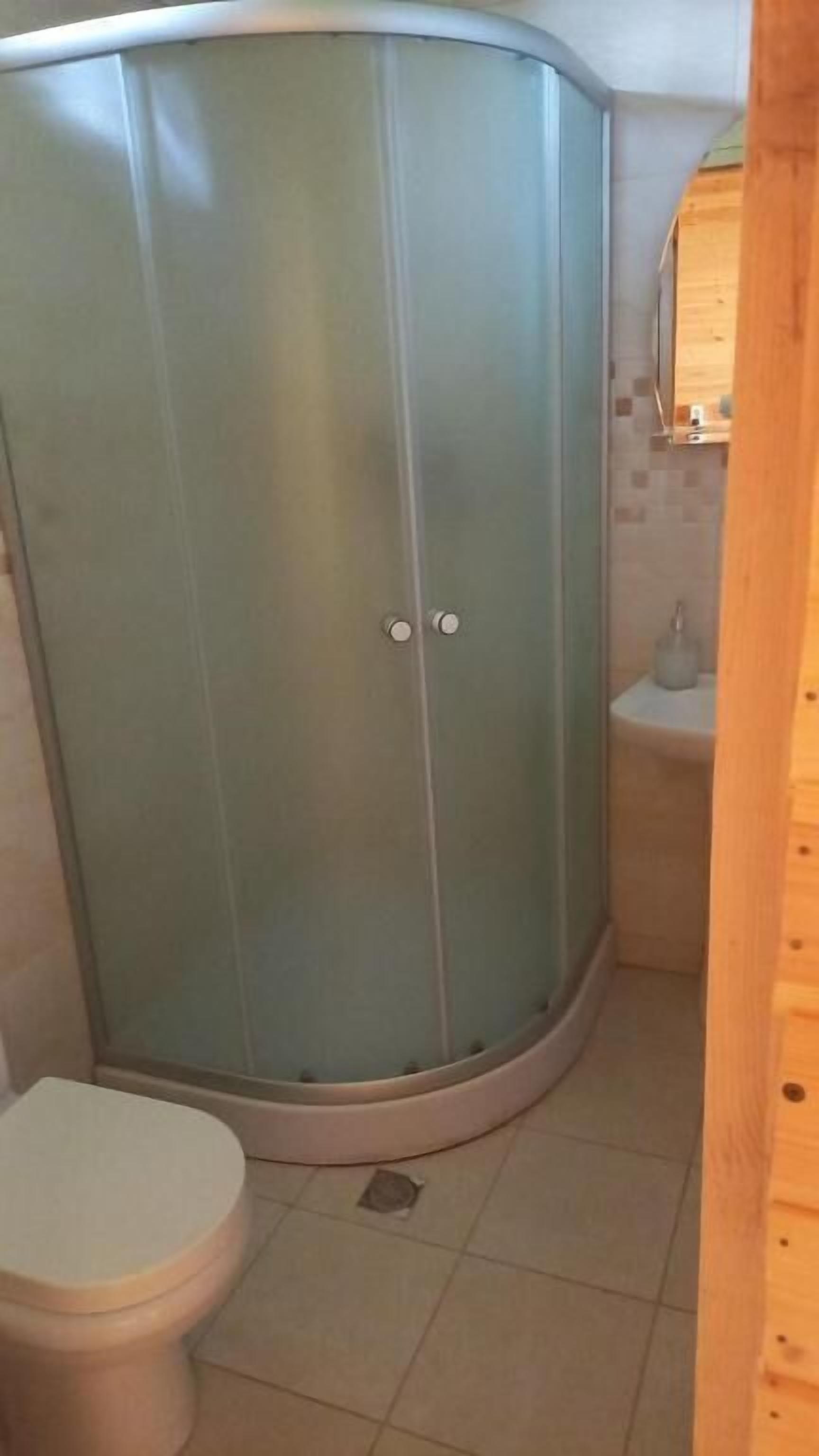 Un baño con cabina de ducha, inodoro y lavamanos.