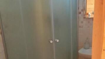 Un baño con cabina de ducha, inodoro y lavamanos.