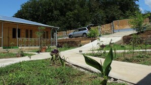 A building with a sloped roof, a paved driveway, and a vehicle parked on a hill. - GREEN VILLA TSKALTUBO (Tsqaltubo)
