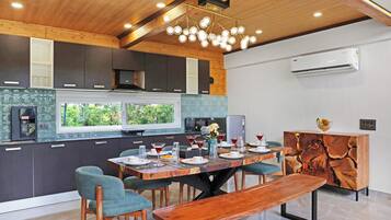 A modern kitchen with dark cabinets, a wooden ceiling, and a dining area with a wooden table and chairs.