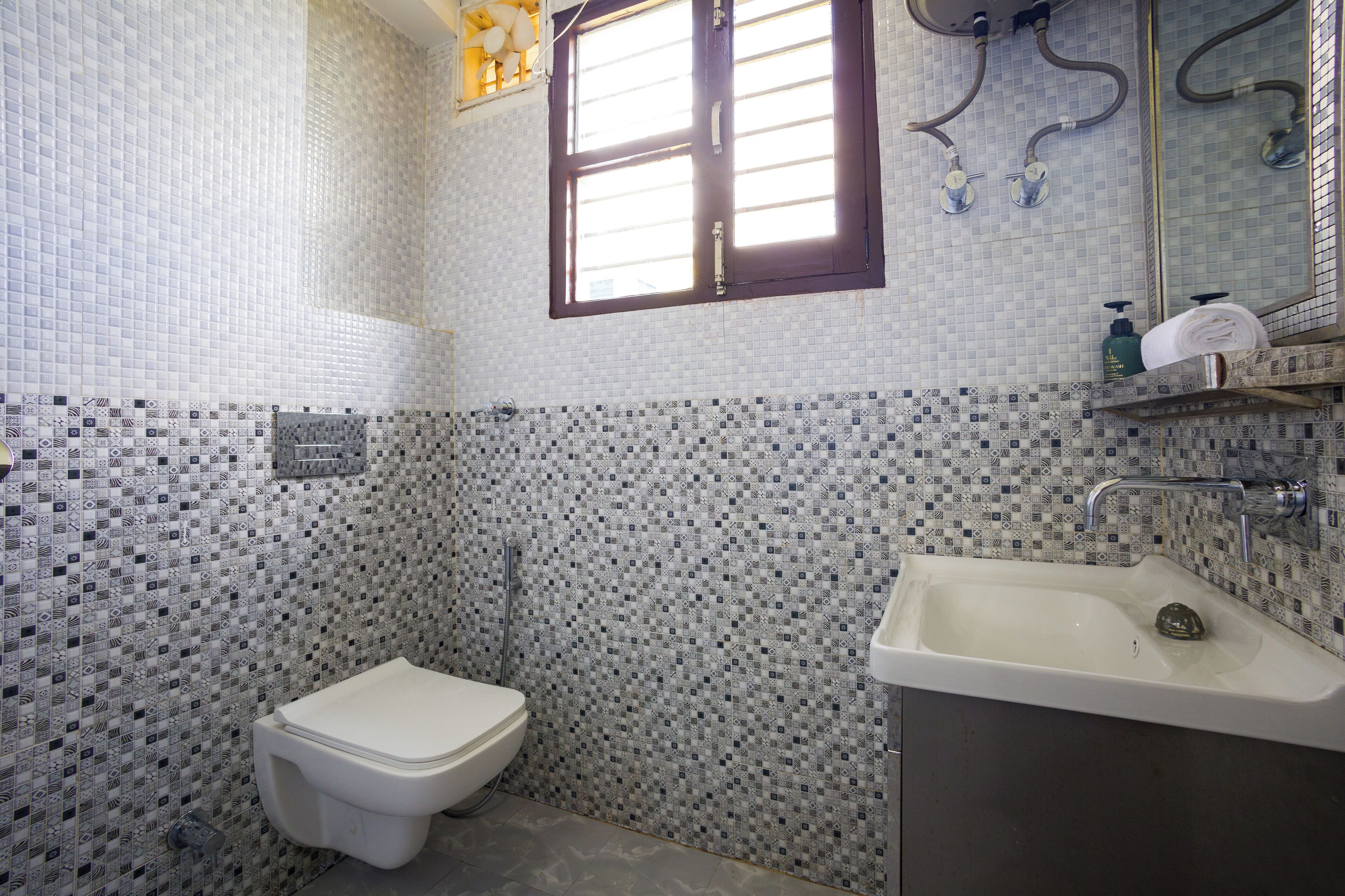 A bathroom with a toilet, sink, and a window.