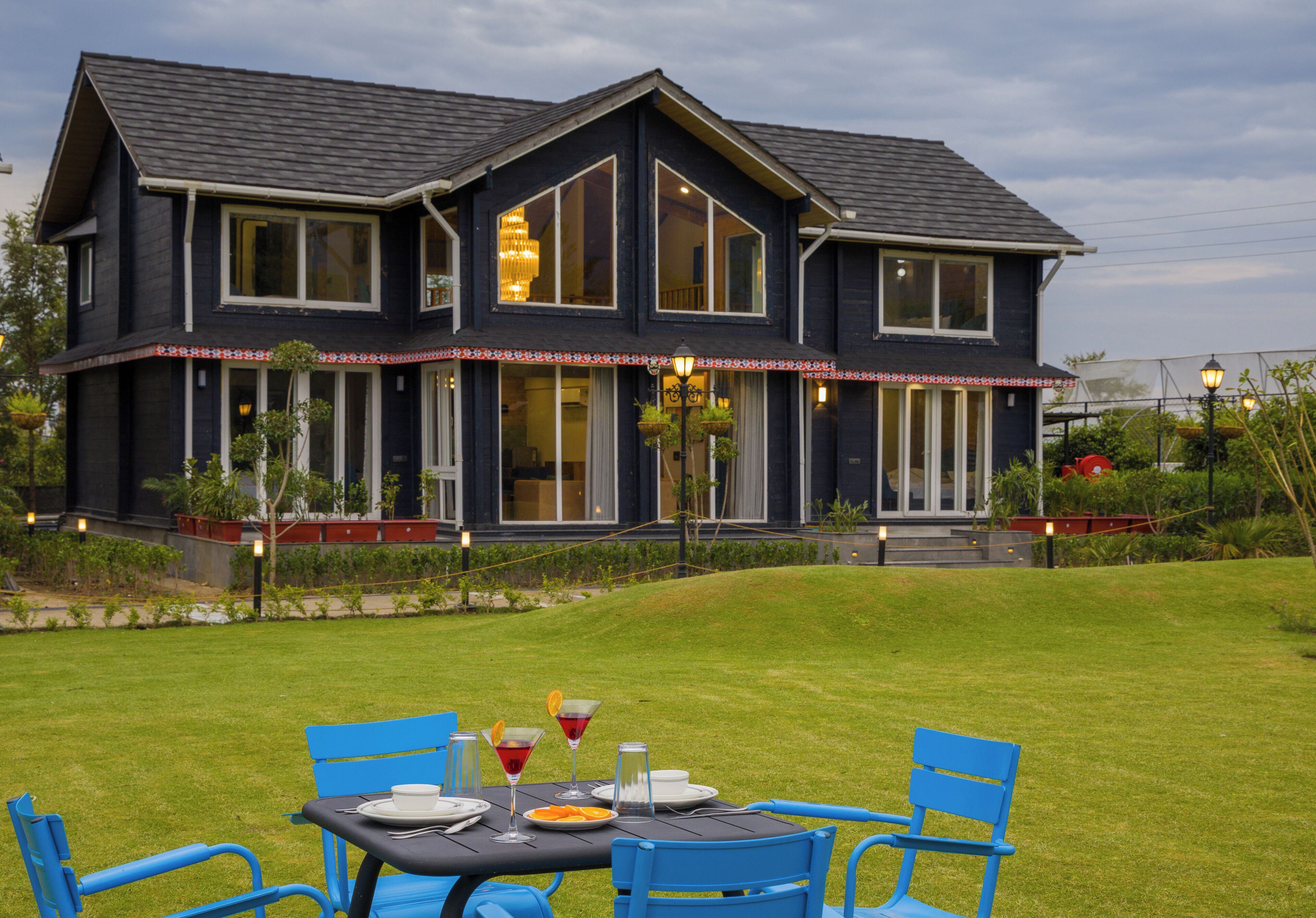 A two-story house with a dark exterior, large windows, and a well-maintained lawn.