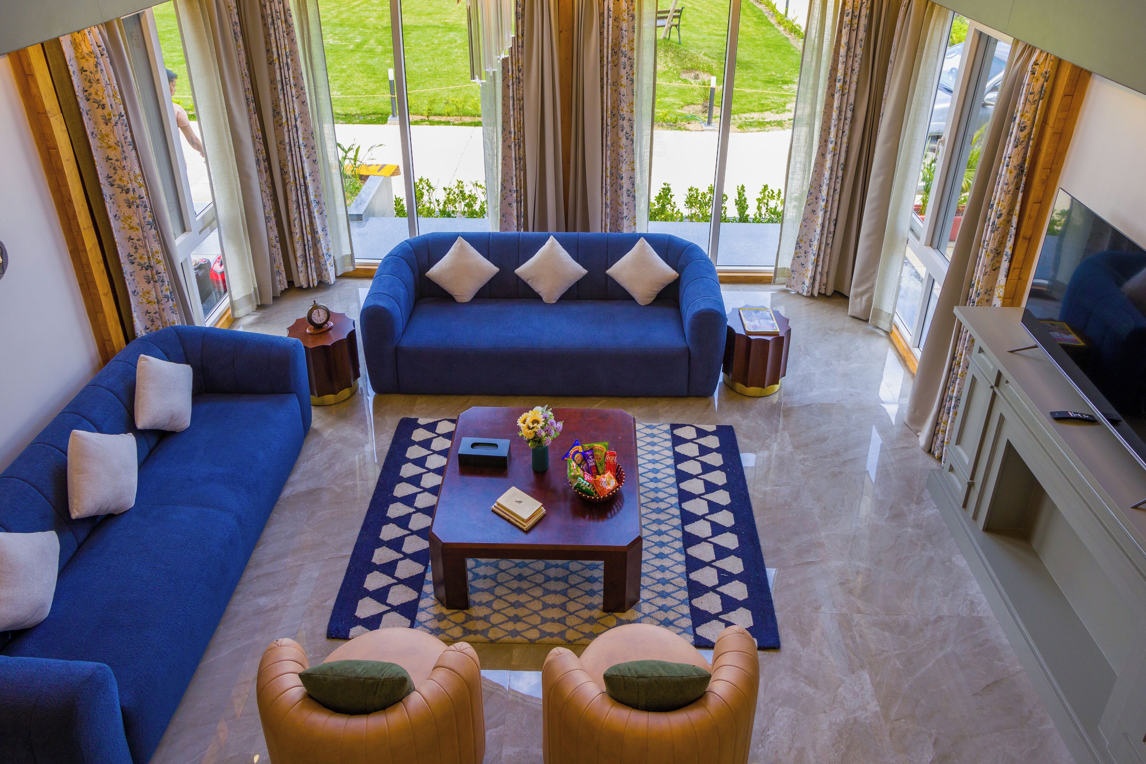 A living room with a blue sofa, two armchairs, a coffee table, and a TV.