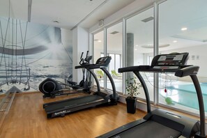 Een fitnessruimte met loopbanden, hometrainers en een roeimachine.
