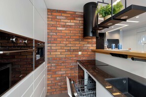Een moderne keuken met een bakstenen muur, een inbouwoven en een vaatwasser.
