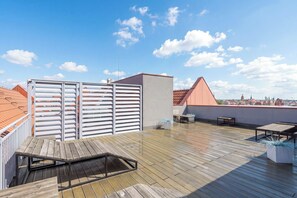 A rooftop terrace with a wooden deck, a metal gate, and a view of the city skyline. - Two-level Apartment in Center | Pool | Gym | Sauna (Gdańsk)