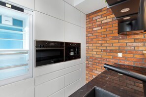 A kitchen with a built-in oven, a refrigerator, and a brick wall backsplash. - Two-level Apartment in Center | Pool | Gym | Sauna (Gdańsk)