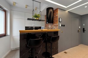A modern kitchen with a bar area, a built-in stove, and a hanging light fixture. - Two-level Apartment in Center | Pool | Gym | Sauna (Gdańsk)