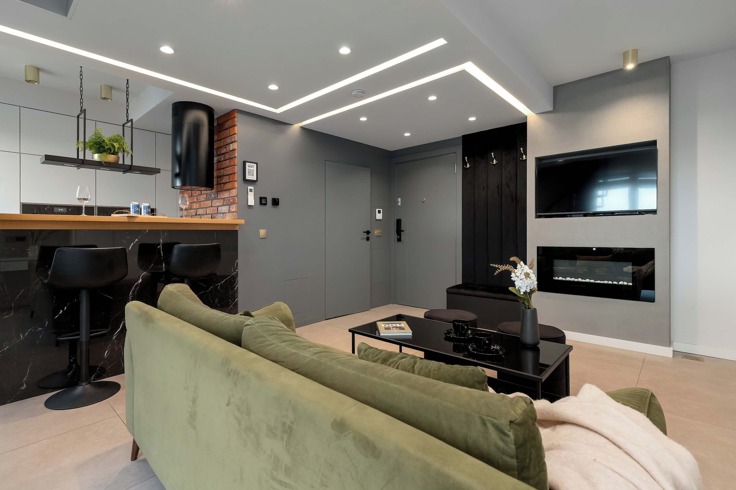 Ein modernes Wohnzimmer mit einer Couch, einem Couchtisch und einem an der Wand montierten Fernseher.