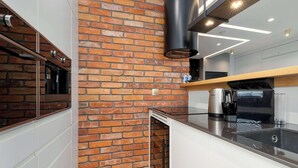 Uma cozinha moderna com parede de tijolos, eletrodomésticos de aço inoxidável e bancada de madeira.
