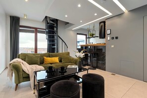 Een moderne woonkamer met een groene bank, een salontafel en een trap naar een bovenverdieping.