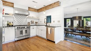 Una cocina moderna con armarios blancos, estufa de acero inoxidable y techo de madera.