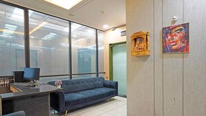 A modern office space with a reception desk, a blue sofa, and a large window.