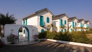 Une rangée de bâtiments blancs agrémentés de touches turquoise, avec des balcons et des portes en arc de cercle.