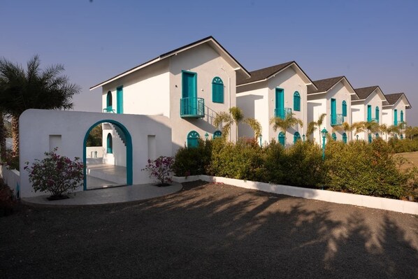 Une rangée de bâtiments blancs agrémentés de touches turquoise, avec des balcons et des portes en arc de cercle.