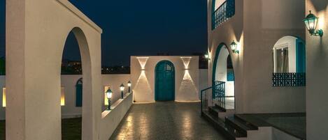 A courtyard with a central door, arched walkways, and illuminated walls.