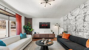 Una sala de estar moderna con un televisor grande, una mesa de centro negra y un mural de mapa.