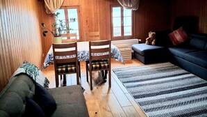 A cozy wooden interior with a dining area, sofa, and a bear decoration. - Lake view Chalet  , Därligen (Interlaken-Oberhasli)
