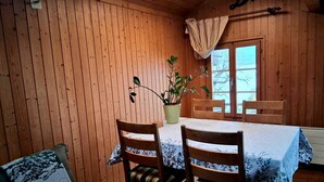 A wooden cabin interior with a dining table, two chairs, a potted plant, and a window with curtains. - Lake view Chalet  , Därligen (Interlaken-Oberhasli)