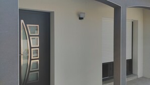 A modern building with a flat roof, a large glass door with a decorative frame, and a small outdoor area with steps leading to a door. - Villa near Les Sables d'Olonne with private pool 15 minutes from the beaches! (Saint-Mathurin)