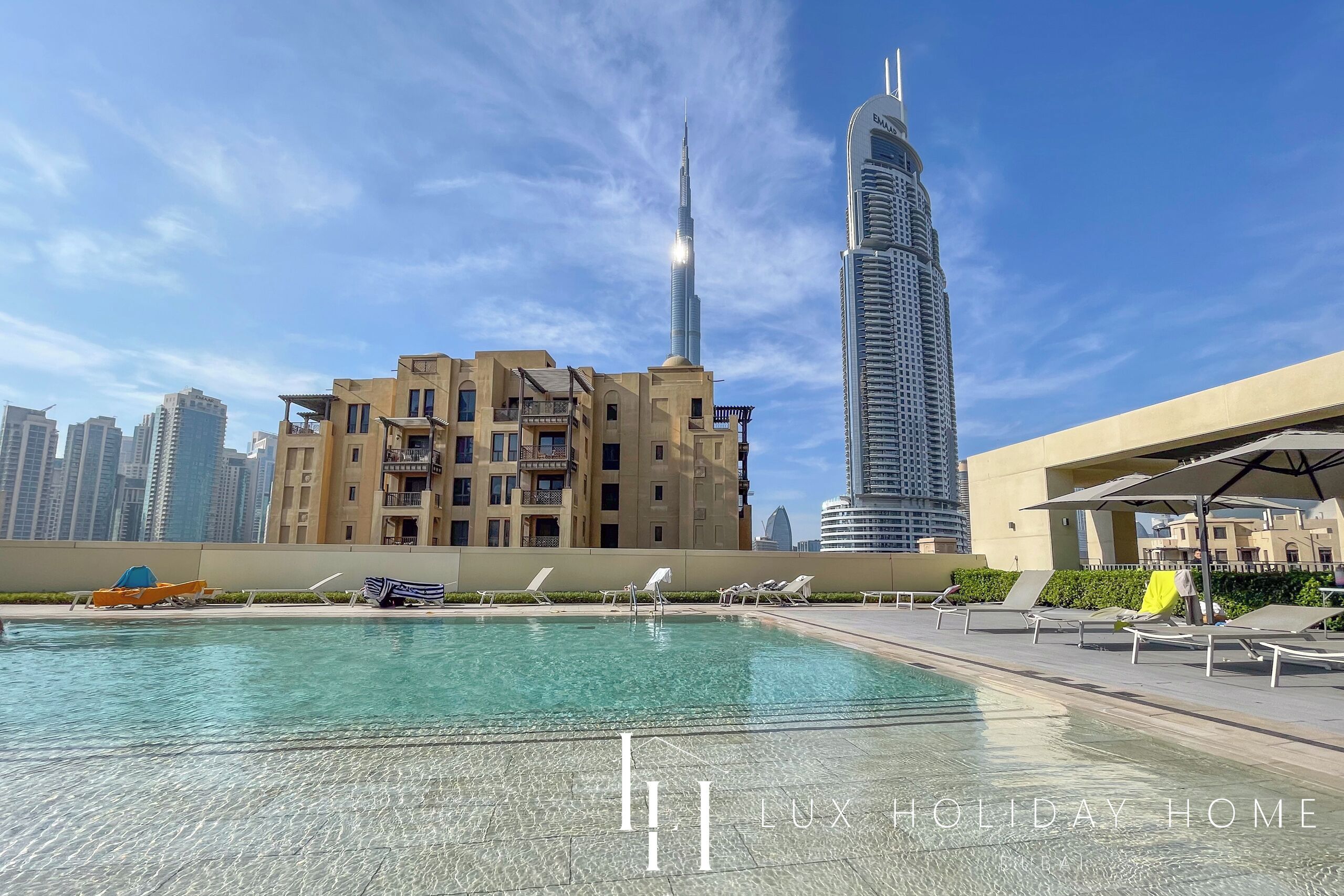A pool area with lounge chairs and a view of the Burj Khalifa.