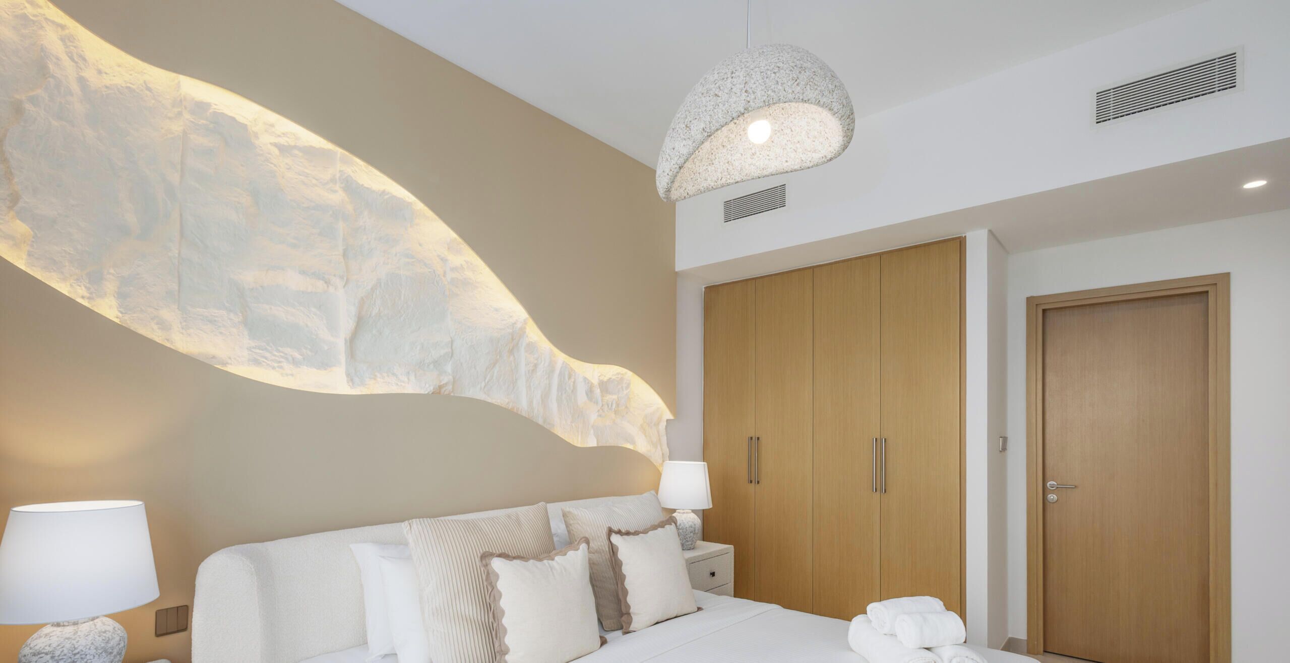 Habitació d'hotel amb un llit gran, un armari de fusta i un element decoratiu únic a la paret.