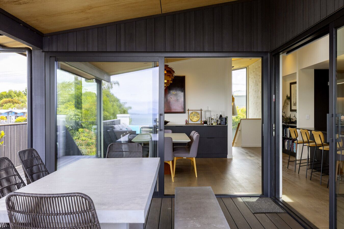 A modern interior with a dining area, kitchen, and a view of the outdoors.