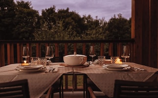 Mesa de comedor al aire libre con vistas a árboles en el fondo.
