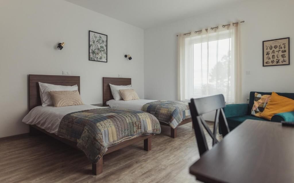 A room with two beds, a dining table, and a sofa.
