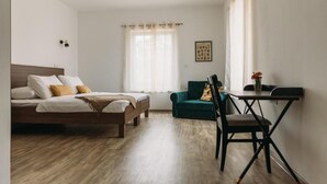 Un dormitorio con cama, escritorio, silla y ventana con cortinas.