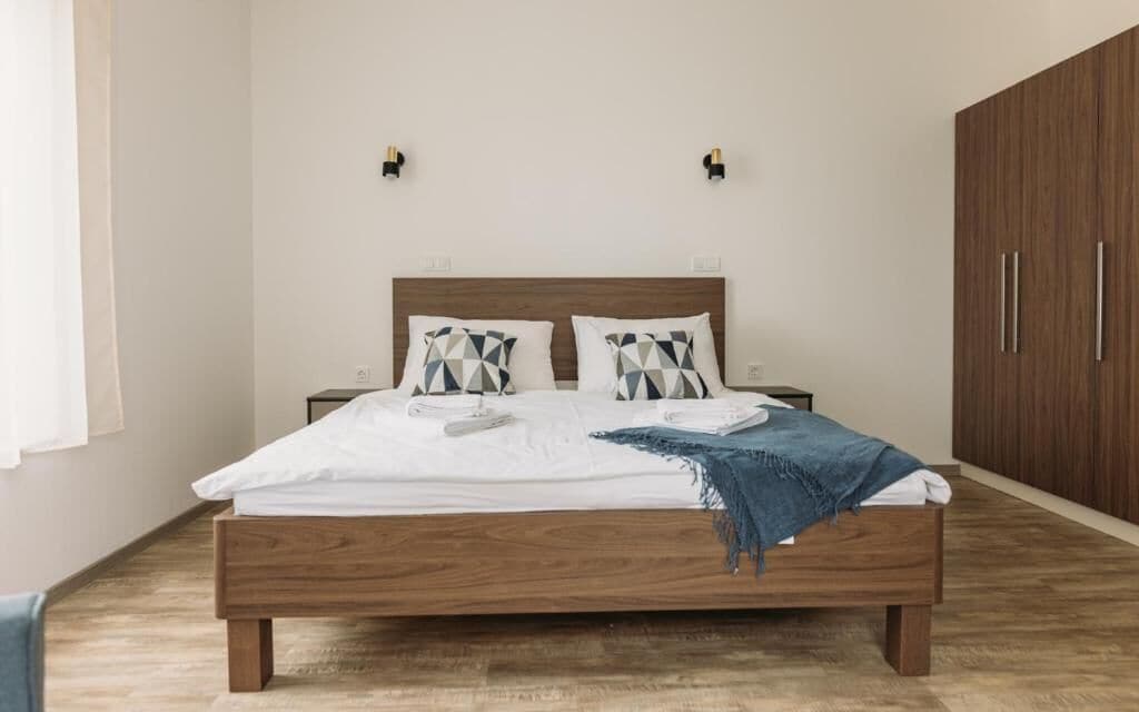 Ein Schlafzimmer mit einem Holzbett, zwei Nachttischen, einem Kleiderschrank und zwei Wandleuchten.