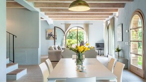 A spacious dining area with a long table, white chairs, and a vase of yellow flowers. - Apartment Azzurro- Cignella Resort Tuscany (Trequanda)
