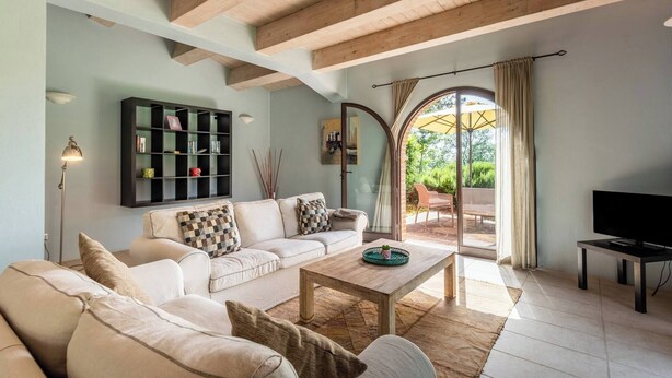 A living room with a sofa, coffee table, and TV. There is a bookshelf and a window with curtains. - Apartment Azzurro- Cignella Resort Tuscany (Trequanda)