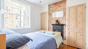 Une chambre avec un mur en briques, une armoire en bois et une cheminée.