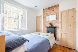 Ein Schlafzimmer mit Backsteinwand, Holzschrank und Kamin.