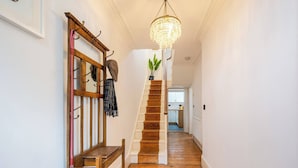 Un escalier en bois, agrémenté d’un lustre, d’un banc et d’une plante sur la plateforme.