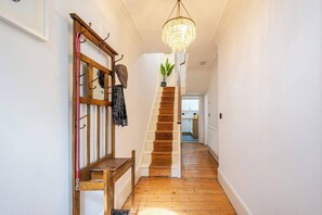 Eine Holzt Treppe mit einem Chandelier, einer Sitzbank und einer Pflanze auf der Zwischenebene.