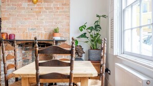 Un coin repas avec un mur en briques, une tête de cerf en guise de décoration, une table, des chaises et des plantes en pot.