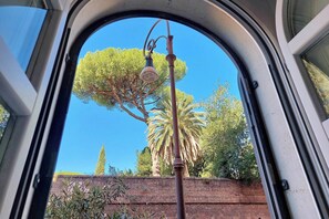A view through a car window, featuring a street lamp, a palm tree, and a brick wall. - Historic Center Rome Colosseum 2BR 2BA Metro (Roma)