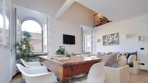 A modern dining area with a wooden table, white chairs, and a view through large windows. - Historic Center Rome Colosseum 2BR 2BA Metro (Roma)