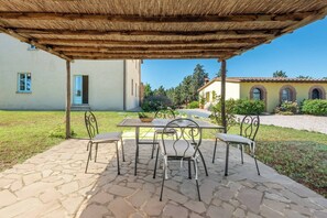 An outdoor patio with stone flooring, a table, and metal chairs. - Apartment Cipresso-Cignella Resort in Tuscany (Siena)