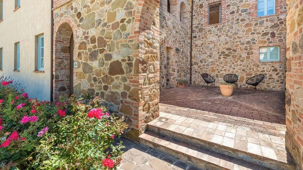 A stone building with a courtyard, featuring a brick pathway and potted plants. - Apartment Cipresso-Cignella Resort in Tuscany (Siena)